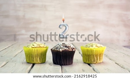 Happy birthday muffins with candles with the number 2. Card copy space with pies for congratulations.