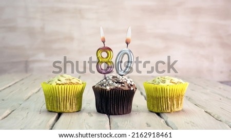 Happy birthday muffins with candles with the number 80. Card copy space with pies for congratulations.