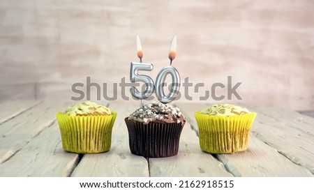 Happy birthday muffins with candles with the number 50. Card copy space with pies for congratulations.