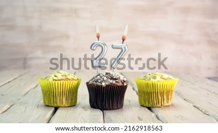 Happy birthday muffins with candles with the number 27. Card copy space with pies for congratulations.
