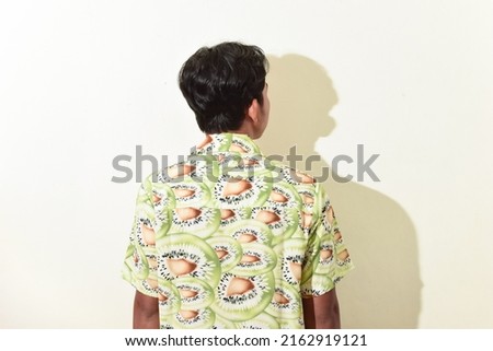 asian man back view. Indonesian man posing with his back to the camera. asian man wearing green hawaiian shirt on white background isolated. stock photos about fashion or traveling