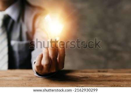 Standing man hold glowing light bulb, Creative new idea. Innovation, brainstorming, strategizing to make the business grow and be profitable. Concept execution, strategy planning and profit management