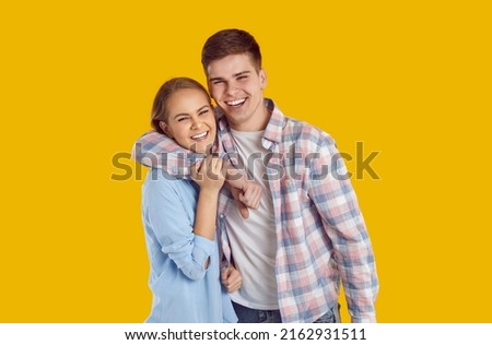 Happy beautiful romantic teenage couple. Older brother and sister with toothy smiles. Handsome Caucasian man and young woman in shirts standing in studio, hugging each other, sharing positive emotions Royalty-Free Stock Photo #2162931511