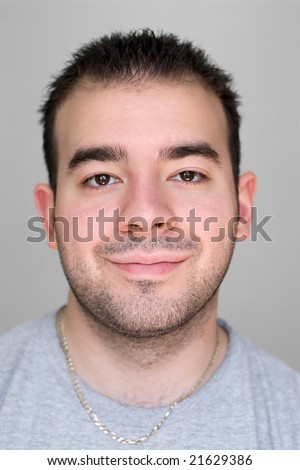 A headshot of a young guy that is smiling isolated on a gray background.