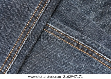Detailed abstract texture of dark blue denim cloth. Background image of old used denim trousers fabric close up