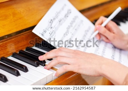 Woman's hands playing piano at home. The woman is professional pianist arranging music using piano keyboards. Musician practicing keyboard composing music. Artist create instrumental acoustic melody. Royalty-Free Stock Photo #2162954587
