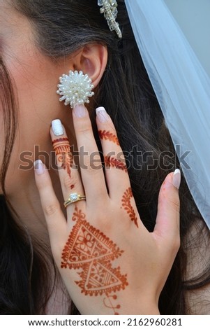 Henna Tattoo on Bride's Hand.Moroccan wedding preparation henna party. Temperate white mehndi. Modern mehendi art.

