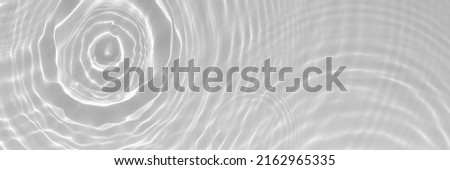 Water texture with sun reflections and water circles on the water surface. Overlay effect for photo or mockup. Organic light gray drop shadow caustic effect. Long banner with copy space. Royalty-Free Stock Photo #2162965335