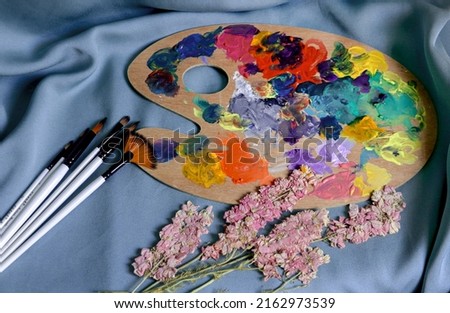 Painting set - brushes and a palette of paints on a blue background
