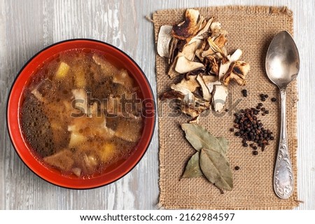 Mushroom soup with dried porcini mushrooms, bay leaf and pepper on rustic table texture background. View from above. Royalty-Free Stock Photo #2162984597