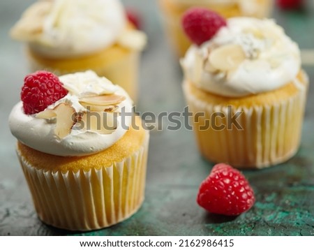 Light healthy dessert - muffins with cream, raspberries and nuts on a dark marble background. Close-up. There are no people in the photo. Birthday, anniversary, wedding, holiday.
