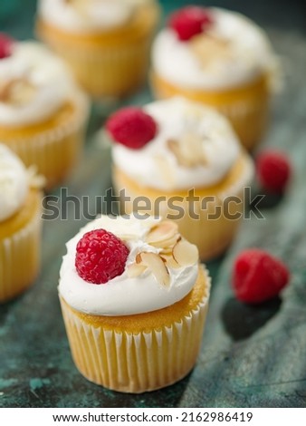 Festive composition. Muffins with cream, raspberries and nuts on a dark background. Restaurant, hotel, cafe, patisserie, cookbook, cookbook, home cooking. Close-up.
