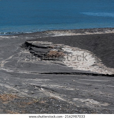 Black beach in Santorini with small river delta formation