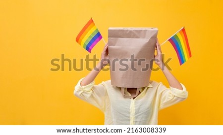 Portrait of shy LGBTQ people covering her face waving rainbow flag for coming out of the closet in pride month to promote marriage equality and differences of homosexual and discrimination Royalty-Free Stock Photo #2163008339