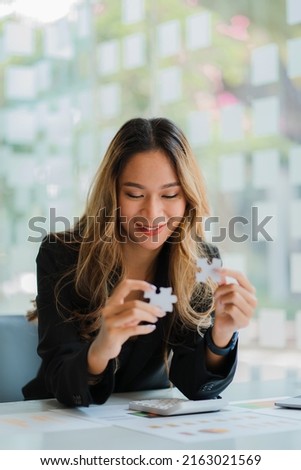 Asian businesswoman playing puzzle symbolic problem solving and working financial accounting work concept. Royalty-Free Stock Photo #2163021569