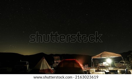 Long exposure of the stars and a camp in the middle of the desert at night.