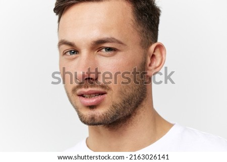 Closeup portrait. Flirted tanned handsome man in basic t-shirt raises eyebrow look at camera posing isolated on white studio background. Copy space Banner Mockup. People emotions Lifestyle concept