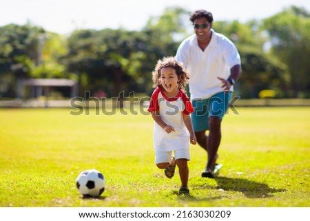 Father and son play football. Dad and little boy play soccer. Young active family enjoy sunny summer day outdoor. Healthy sport for kids. Football game club. Royalty-Free Stock Photo #2163030209