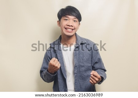 Portrait of handsome man in gray shirt with cheerful face showing victory