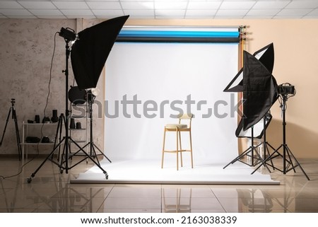 Lighting equipment, chair and cyclorama in modern photo studio