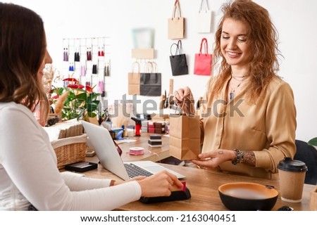 Female business owner serving client in shop
