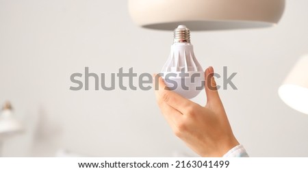 Woman changing light bulb of chandelier at home