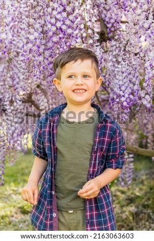 Little boy near blooming tree in garden 