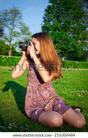 Girl with the camera in the park smiling and looking happy
