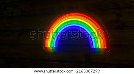 led neon rainbow hanging on the wooden wall