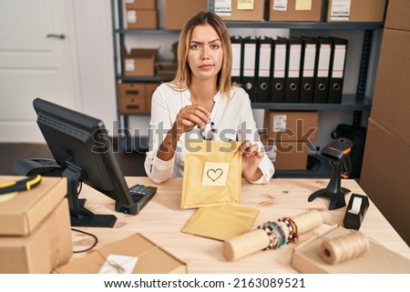 Young blonde woman working at small business ecommerce skeptic and nervous, frowning upset because of problem. negative person. 