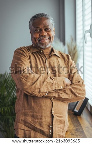 Portrait of an older man wearing a shirt on a gray background. A happy old man looks at a camera isolated over a gray wall. An older man smiles at the camera, a happy old man.  Royalty-Free Stock Photo #2163095665