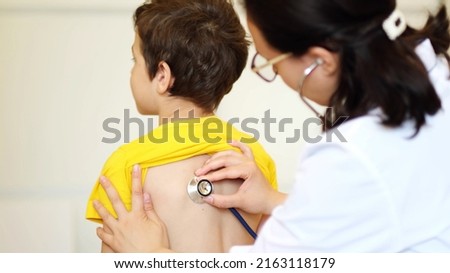 doctor listens to breath of little boy through stethoscope. Pediatrician with stethoscope listening to a lungs in child with bronchitis and cough Royalty-Free Stock Photo #2163118179