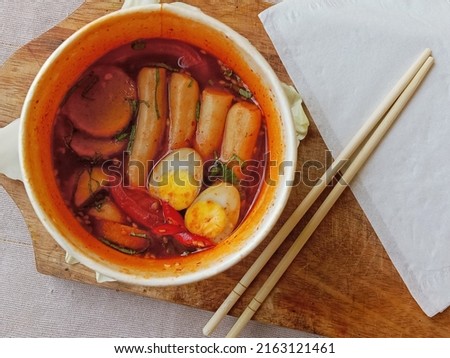 top angle picture of chopsticks and korean rice cakes, a popular korean street food dish with red spicy sauce 