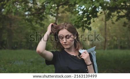 A girl poses by the forest on a warm summer evening.