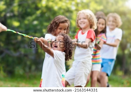 Kids play tug of war in sunny park. Summer outdoor fun activity. Group of mixed race children pull rope in school sports day. Healthy outdoor game for little boy and girl. Royalty-Free Stock Photo #2163144331