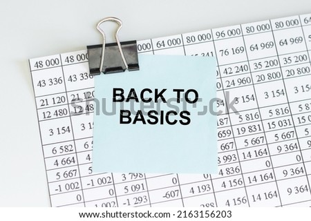 BACK TO BASICS text on a blue card clip to a sheet with numbers on a light table, business concept