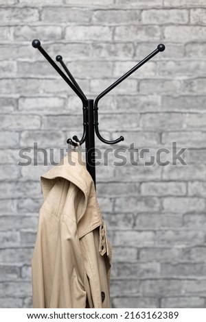 beige raincoat hanging on the hook of a floor hanger. High quality photo