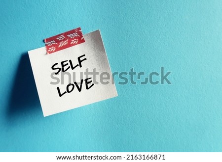 Paper note stick on blue copy space background with handwritten text SELF LOVE, refers to self worth, being confidence with self-esteem - giving yourself respect, dignity and understanding Royalty-Free Stock Photo #2163166871