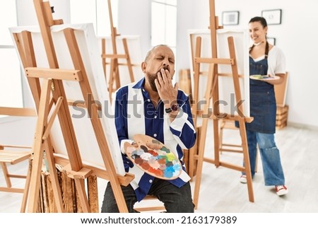 Senior artist man at art studio bored yawning tired covering mouth with hand. restless and sleepiness. 