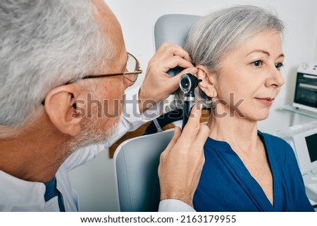 Otolaryngologist doctor checking senior woman's ear using otoscope or auriscope at medical center. Hearing test for older people, otoscopy Royalty-Free Stock Photo #2163179955