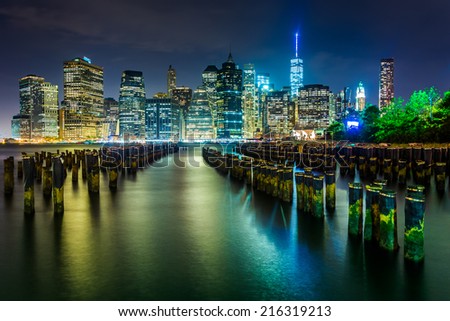 Pier pilings and the Manhattan skyline at night, seen from Brooklyn Bridge Park, New York.