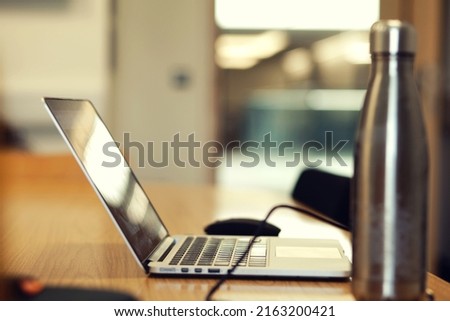 Work desk laptop next to with water canteen inside college study room Royalty-Free Stock Photo #2163200421