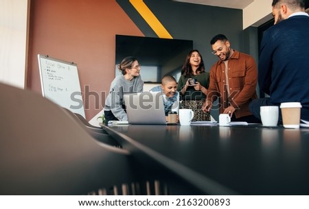 Successful businesspeople discussing some reports in a boardroom. Group of multicultural businesspeople standing around a table in a modern office. Diverse entrepreneurs collaborating on a project. Royalty-Free Stock Photo #2163200893