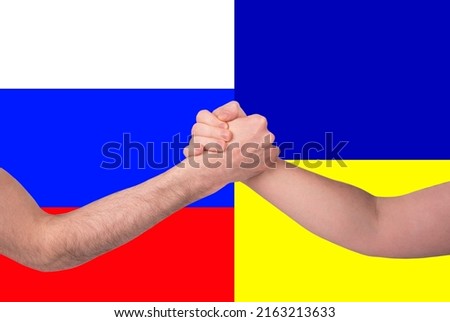 Two men's hands in a fight arm wrestling against the background of the Ukrainian and Russian flag