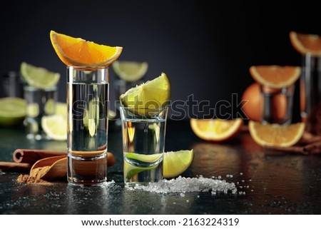 Various ways of using tequila. Tequila with lime and salt and tequila with orange and cinnamon. Royalty-Free Stock Photo #2163224319