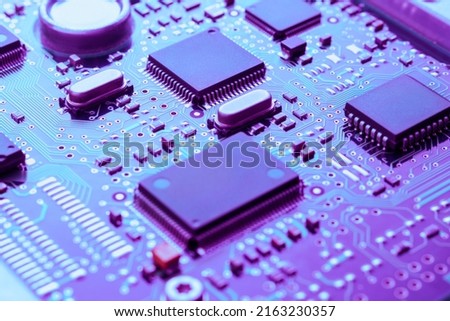 High tech technology background with printed circuit board PCB, chips and many electronic components toned blue and purple, selective focus.