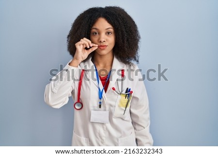 Young african american woman wearing doctor uniform and stethoscope mouth and lips shut as zip with fingers. secret and silent, taboo talking 