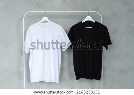 Black and white T-shirt hanging on a hanger, layout Royalty-Free Stock Photo #2163233151