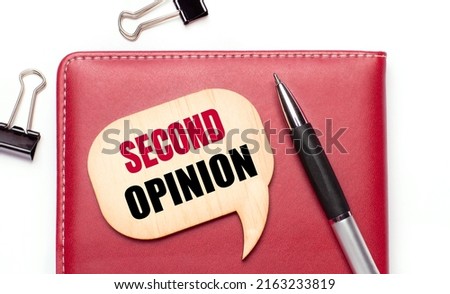 On a light background there are black paper clips, a pen, a burgundy notepad a wooden board with the text SECOND OPINION