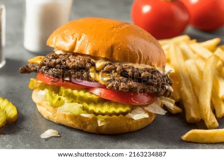 Homemade Cheese Smash Burger with Fries Pickles and Tomatoes Royalty-Free Stock Photo #2163234887